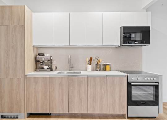 A modern kitchen with wooden cabinets and stainless steel appliances at Aria, New York, NY