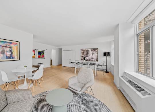A living room with a grey couch, white chairs, and a coffee table at Aria, New York, NY