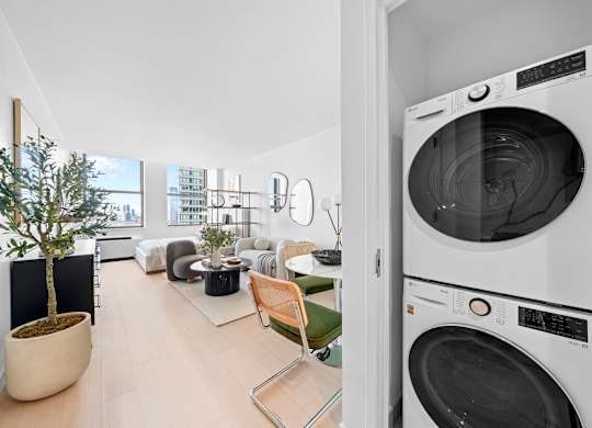 A modern laundry room with a washer and dryer stacked on top of each other at One West, New York, New York.