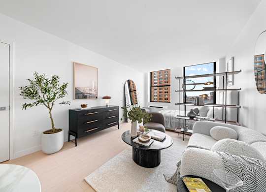 A living room with a white couch, a coffee table, and a plant. at One West, New York
