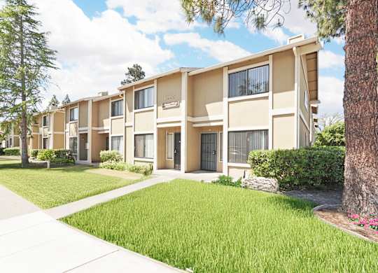 Apartment complex with green grass and trees.