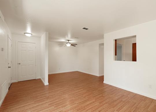 A room with a ceiling fan and wooden flooring.