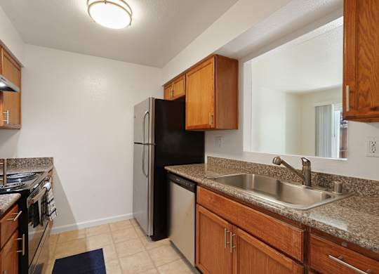A kitchen with a black refrigerator and wooden cabinets.