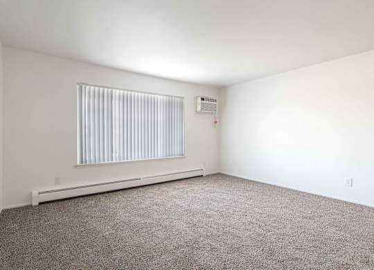 A room with a window covered by blinds and a wall-mounted air conditioner unit.