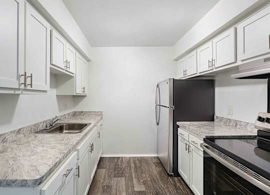 A kitchen with white cabinets and a marble countertop.