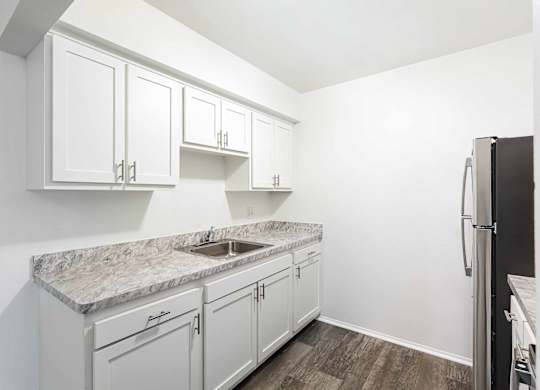 A kitchen with white cabinets and a granite countertop.