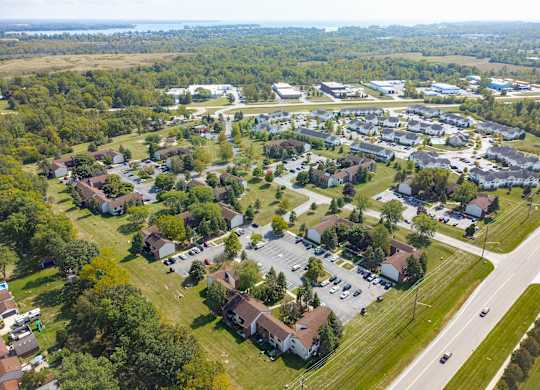 A bird's eye view of a residential area with houses, trees, and a road.