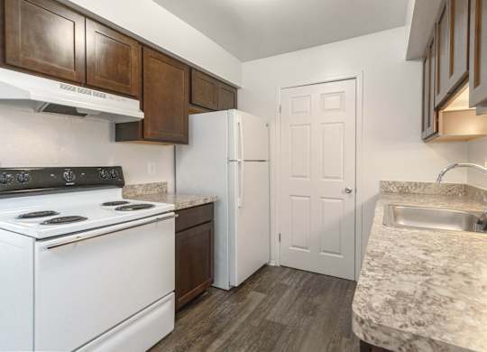 A kitchen with a white stove top oven and a white refrigerator.