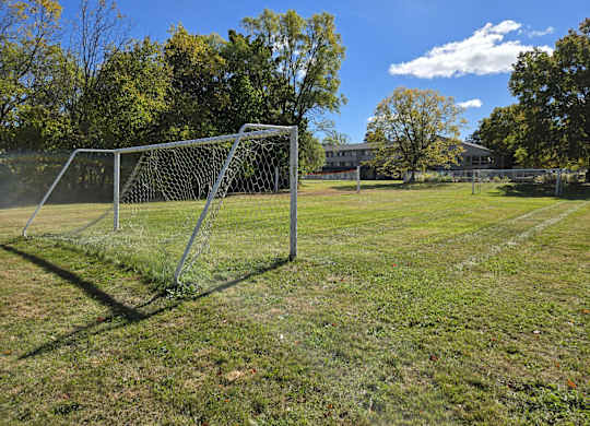 a soccer goal on a field with a house in the background