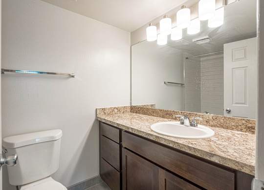 A bathroom with a toilet, sink, and mirror.