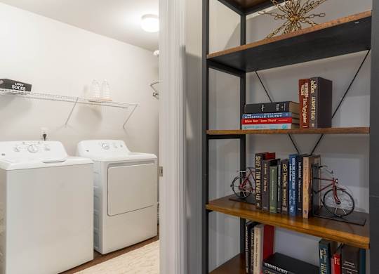 a laundry room with a washer and dryer and a book shelf with books