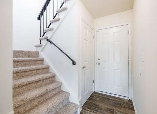 A white door is in a hallway next to a staircase.