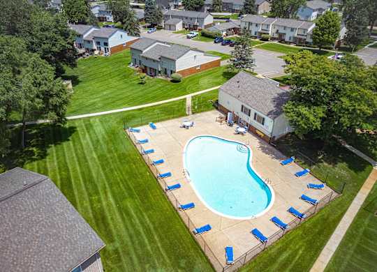 A swimming pool surrounded by blue lounge chairs in a grassy area.