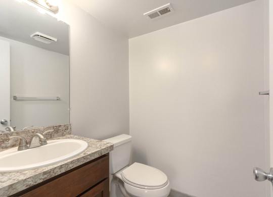 A bathroom with a toilet, sink, and mirror.