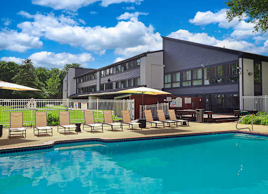 A swimming pool in front of a building with sun loungers.