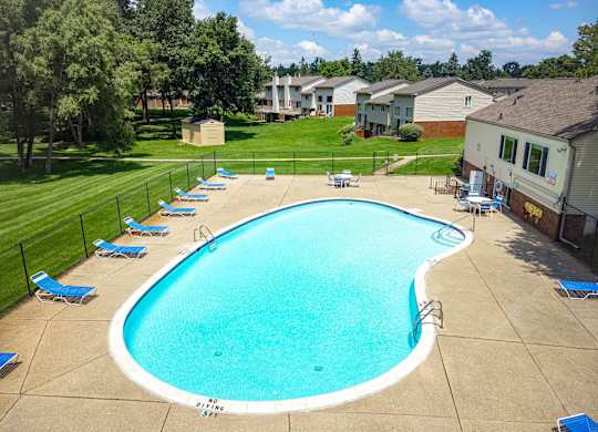 A large swimming pool surrounded by a fence and trees.