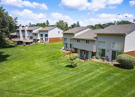A grassy field with a few houses in the background.