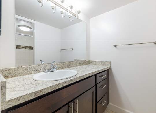 A bathroom with a sink, mirror, and a towel bar.