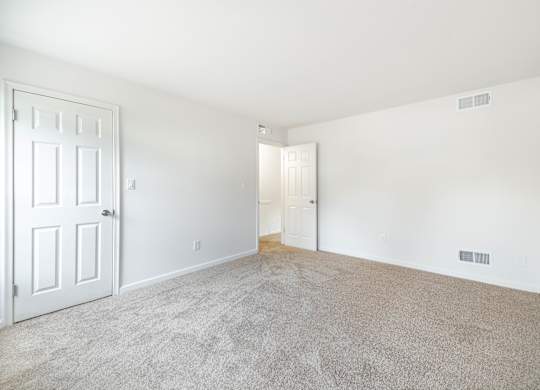 A room with a carpeted floor and a white door.