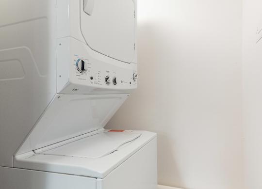 A white dryer is sitting in a room with a white wall.