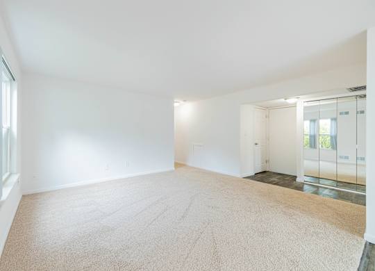 A large empty room with a carpeted floor and white walls.