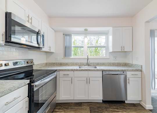 A kitchen with white cabinets and a black stove top oven.