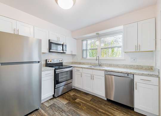 A kitchen with a stainless steel refrigerator, microwave, oven, and dishwasher.
