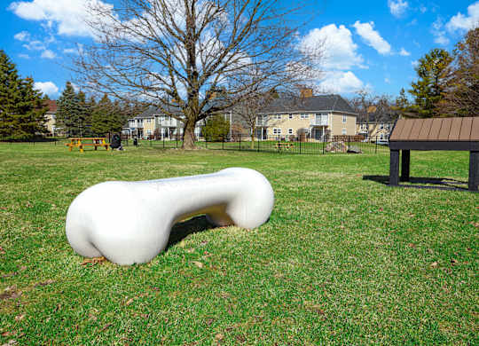 A white, curved bench sits in a grassy field.