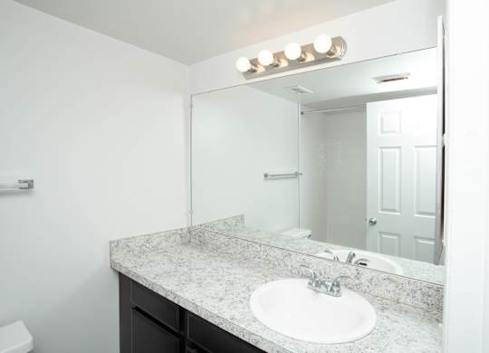 A bathroom with a sink, mirror, and lights.