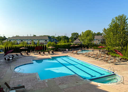 A large swimming pool surrounded by lounge chairs and trees.