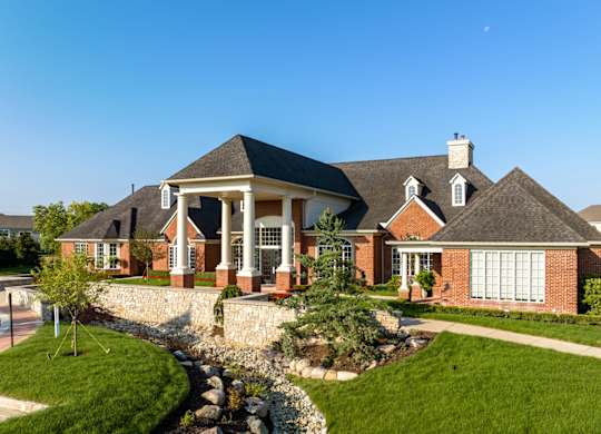a large brick house with a front porch and a landscaped yard