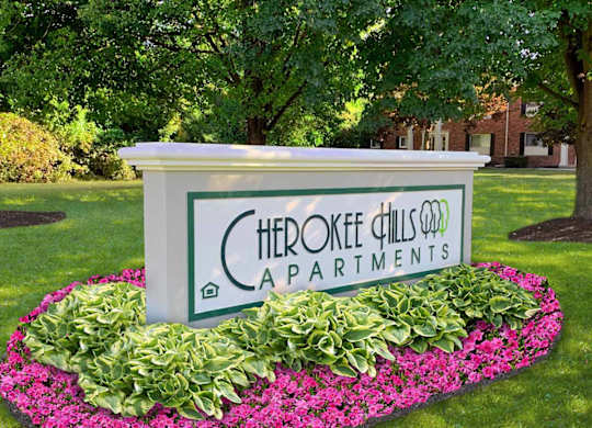 A sign for Cherokee Hills Apartments is surrounded by flowers.