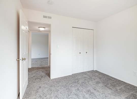 A white door is open to a room with a carpeted floor.