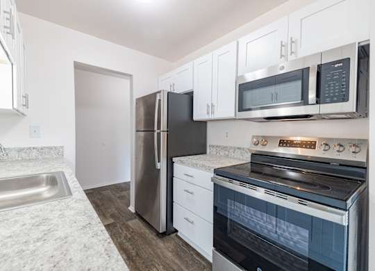 A kitchen with a stainless steel refrigerator, oven, and microwave.