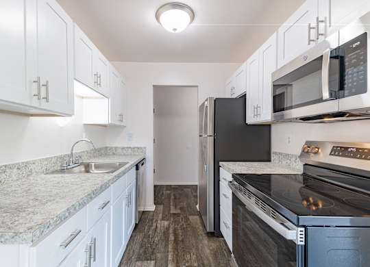 A kitchen with white cabinets and a black refrigerator.