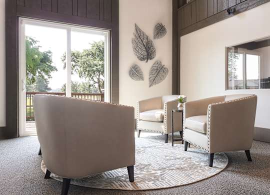 A living room with a large chair and a smaller chair with a table in between.