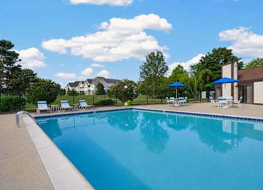 A large swimming pool with a blue sky and clouds reflected in the water.