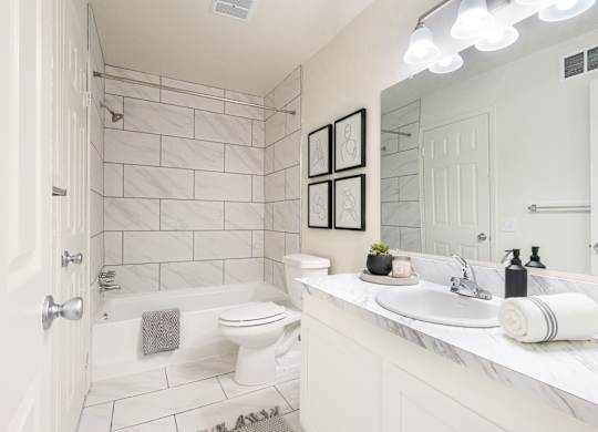A white bathroom with a toilet, sink, and shower.