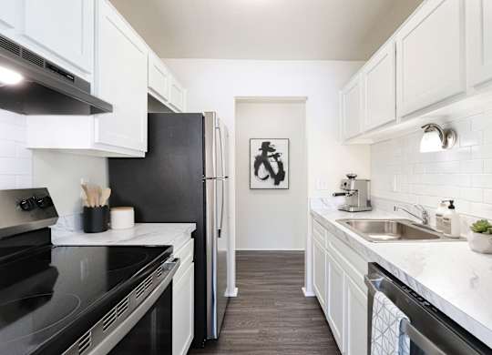 A kitchen with black appliances and white cabinets.