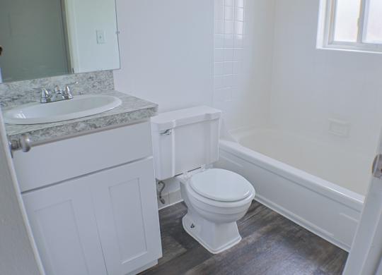 A white toilet sits in a bathroom next to a sink and bathtub.