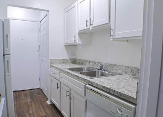 A kitchen with white cabinets and a marble countertop.