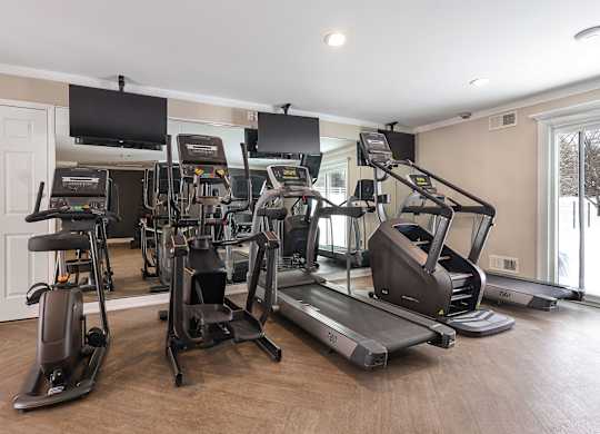 A home gym with treadmills, elliptical machines, and other exercise equipment.