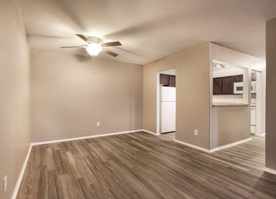 A room with a ceiling fan and wooden flooring.