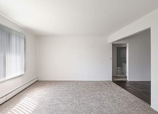 A large, empty room with a carpeted floor and a doorway leading to another room.