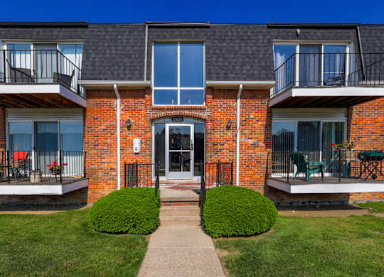 A red brick building with a black roof and a small front yard.