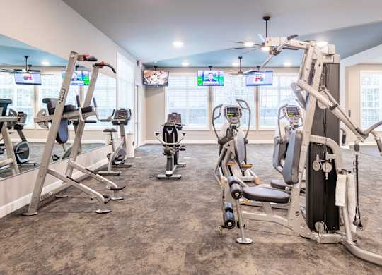 A gym with a variety of exercise equipment including treadmills, stationary bikes, and weight machines.