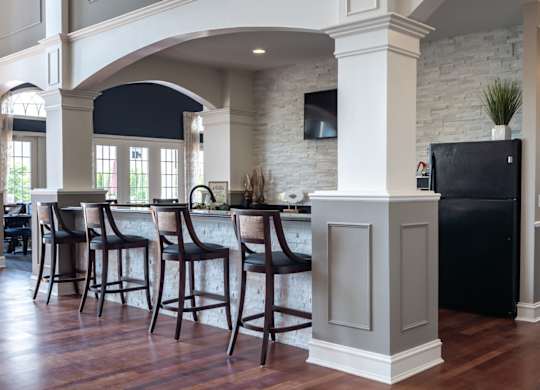 A kitchen with a black fridge and wooden floors.