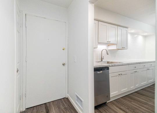 A kitchen with white cabinets and a wooden floor.