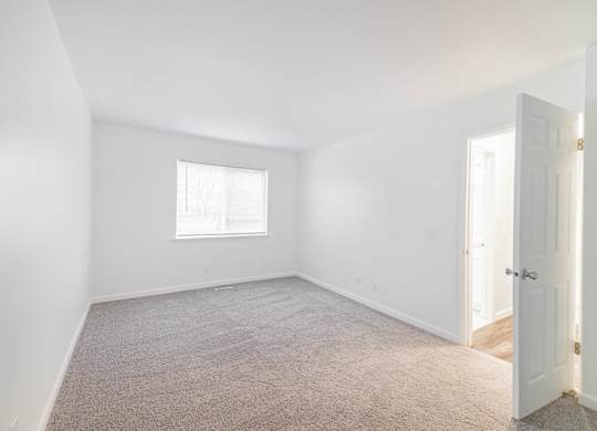 A room with a carpeted floor and a window.