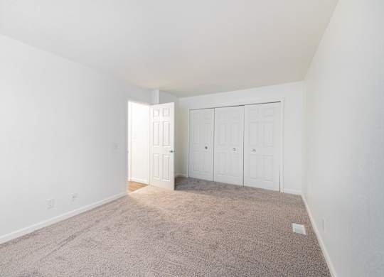 A room with white walls and carpeted floor with a doorway open.